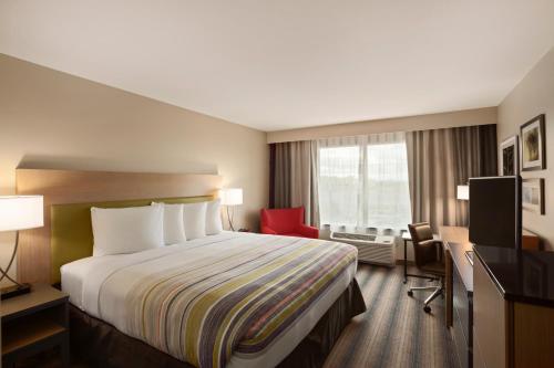 a hotel room with a bed and a red chair at Country Inn & Suites by Radisson, Houghton, MI in Houghton