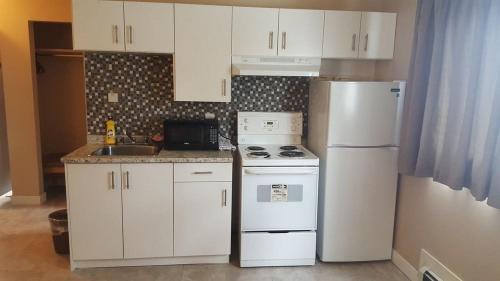 a kitchen with white cabinets and a white refrigerator at Sunrise Motel in Regina