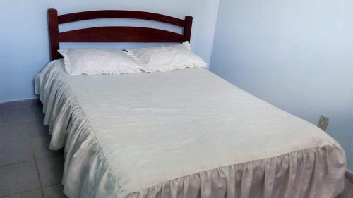 a bed with white sheets and pillows in a room at Ubatuba Apartamento Maurilio in Ubatuba
