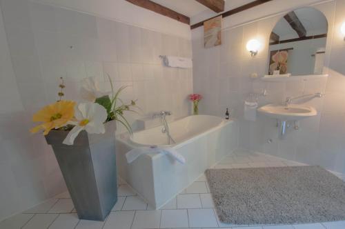 baño con bañera, lavabo y jarrón con flores en Gästehaus Wahnenmühle en Erkrath