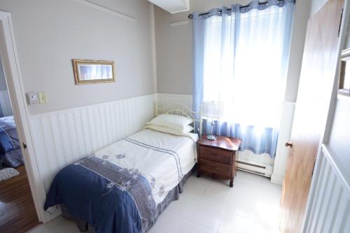 a small bedroom with a bed and a window at Auberge le St-Georges in Saguenay