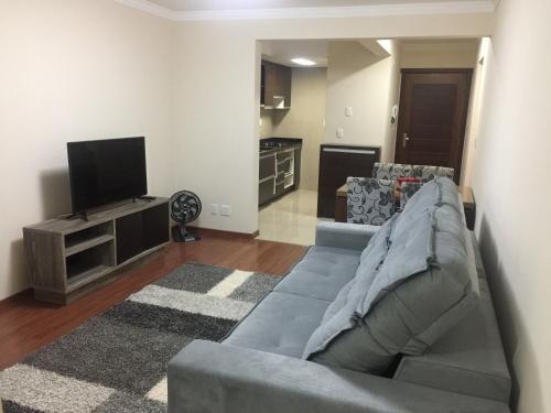 a living room with a couch and a flat screen tv at Apartamento Baviera in Canela