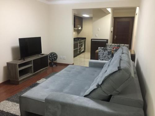 a living room with a couch and a flat screen tv at Apartamento Baviera in Canela