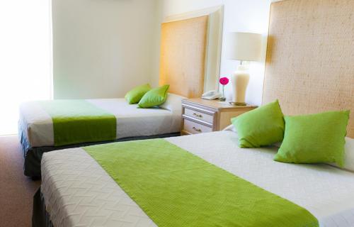 duas camas num quarto de hotel com almofadas verdes em Hotel de Casa Blanca em Lázaro Cárdenas