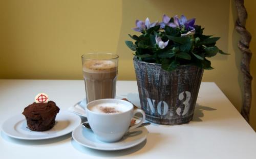 a table with a cup of coffee and a vase with flowers at PilgrimsHuset Maribo in Maribo