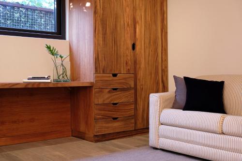 a living room with a wooden cabinet next to a chair at El Callejón Hotel Boutique in Oaxaca City