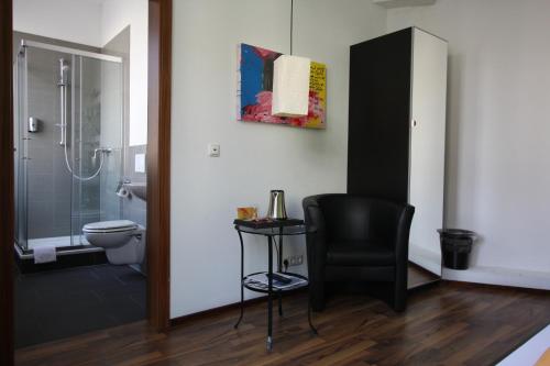 a bathroom with a toilet and a black chair at Stadthotel Kleiner Berg in Friedrichshafen