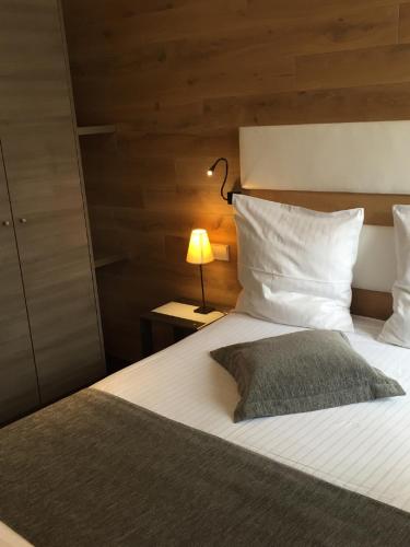 a bedroom with a large white bed with a lamp at Hôtel L'Auberge Alsacienne in Eguisheim