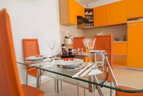 a dining room table with plates and glasses on it at Apartments Mia in Baška
