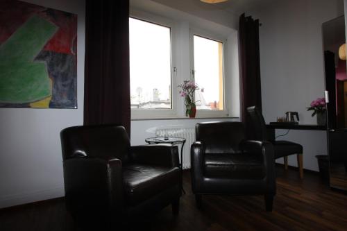 a living room with two chairs and a window at Stadthotel Kleiner Berg in Friedrichshafen