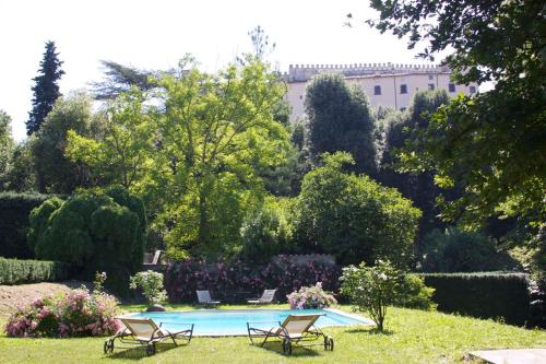 a swimming pool with two chairs in a garden at Castello Costaguti in Roccalvecce