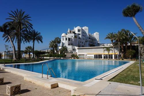 duży basen z palmami i budynek w obiekcie Castillo de Santa Clara w mieście Torremolinos