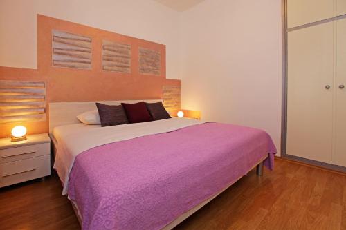 una camera da letto con un grande letto con una coperta viola di Katica apartments a Bol