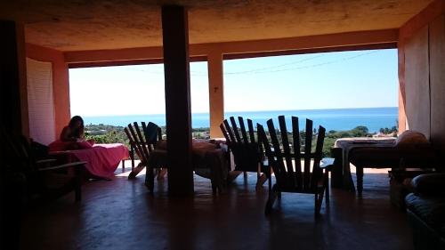 a woman sitting at a table in a room with chairs at Welcoming vibes in Treasure Beach