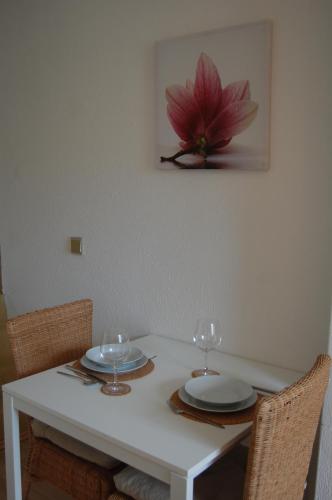 a white table with two plates and wine glasses at Hofgassl Zentgraf in Mörbisch am See