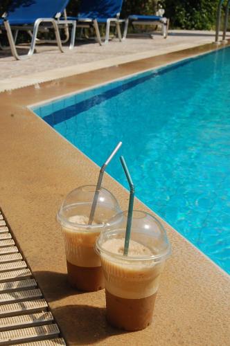 two drinks are sitting next to a swimming pool at Violetta Hotel in Amoudara Herakliou