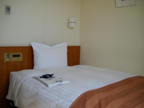 a bedroom with a white bed with a pair of glasses on it at Hotel Kunimi Gotenba in Gotemba