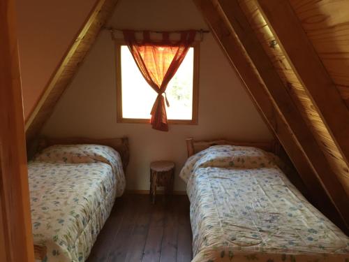 two beds in a attic room with a window at Cabañas del Michay in Tolhuin