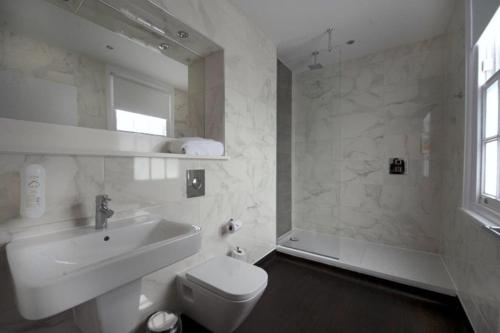 Baño blanco con lavabo y aseo en The Greenwood Hotel - Wetherspoon en Northolt