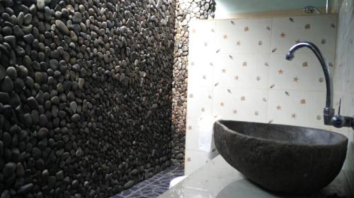 Labuhan Pandanにあるポンドック シオラの石造りの洗面台と壁が備わるバスルーム