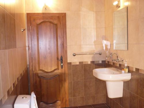a bathroom with a wooden door and a sink at Hotel Asenevtsi in Veliko Tŭrnovo