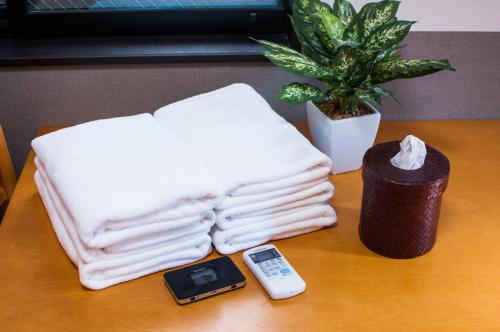a pile of towels and a cell phone on a table at Guest House One More Heart Kyoto Station South 1 in Kyoto