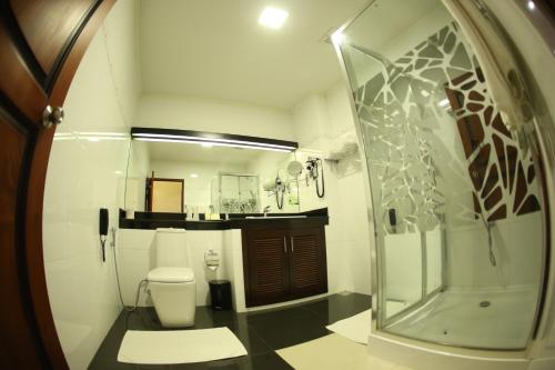 a bathroom with a shower and a toilet and a mirror at Kandyan Reach Hotel in Kurunegala