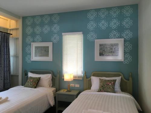 a bedroom with two beds and a blue wall at Bann Vimansamutr in Cha Am