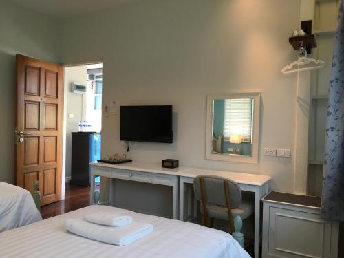 a bedroom with a desk with a tv and a bed at Bann Vimansamutr in Cha Am
