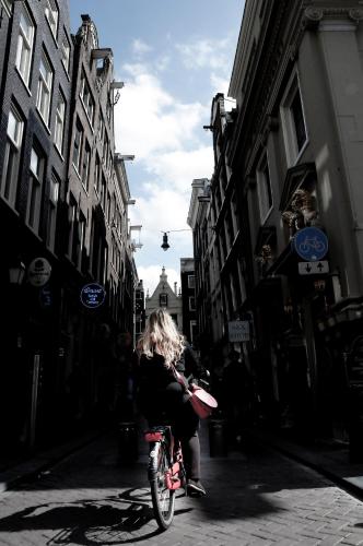 a woman riding a bike down a street at Budget Hotel Ben in Amsterdam