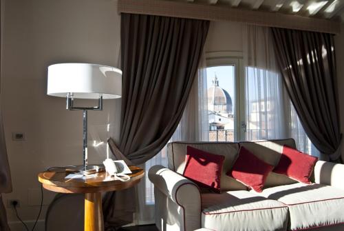sala de estar con sofá y mesa con lámpara en Hotel Patria, en Pistoia
