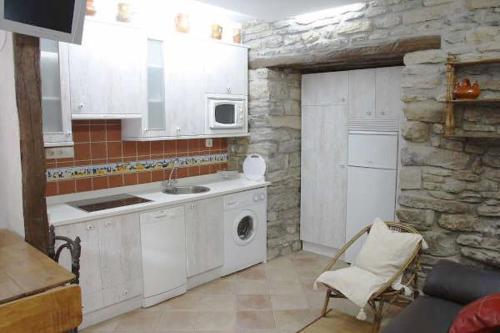 cocina con electrodomésticos blancos y pared de piedra en Apartamentos Rurales Rincón de Aiara, en Menagaray