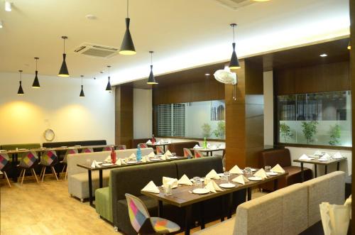 a restaurant with tables and couches and chairs at Hotel Vintage in Vadodara