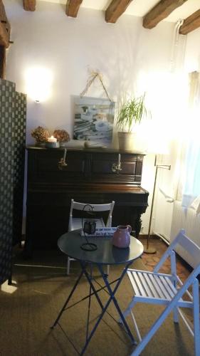 una mesa y sillas en una habitación con piano en Le Gite de Laurence, en Sainte-Livière