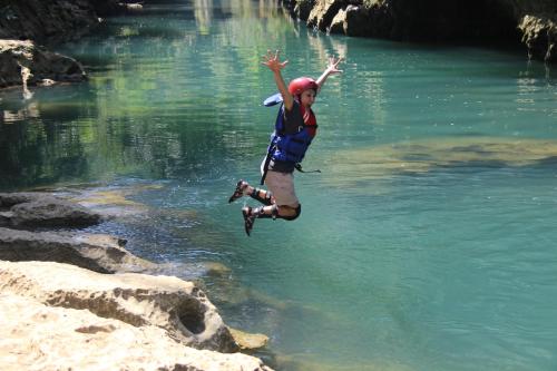 a boy jumping into a river with a frisbee at Jelajah Batukaras in Batukaras