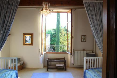 a bedroom with two beds and a large window at Bastide le Luget in Vénéjan