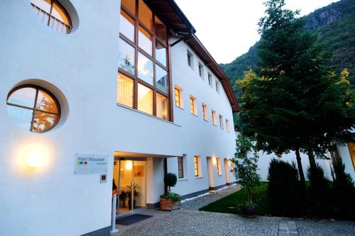 a white building with a door and a tree at Hotel Masatsch in Caldaro