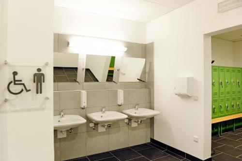 a bathroom with three sinks and a mirror at Hotel Masatsch in Caldaro