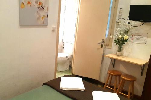 a bathroom with a toilet and a table and two stools at Hostal Lima in Barcelona