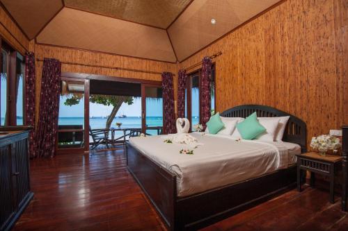 a bedroom with a bed with a view of the ocean at Palm Leaf Resort Koh Tao in Ko Tao