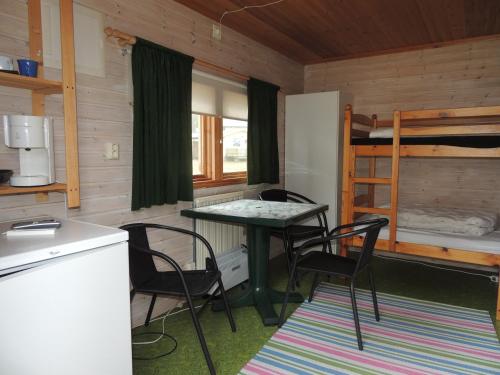 eine Küche mit einem Tisch und Stühlen sowie ein Etagenbett in der Unterkunft Alholmens Camping & Stugby in Sölvesborg