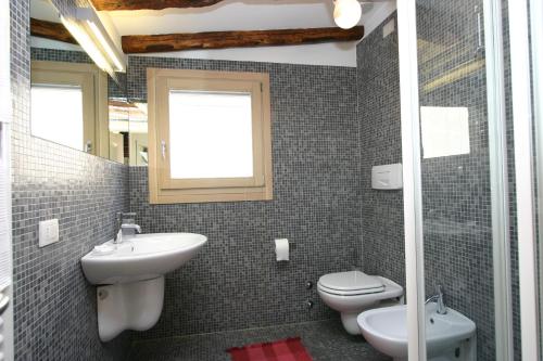 een badkamer met een wastafel, een toilet en een raam bij Casa Alba in Venetië