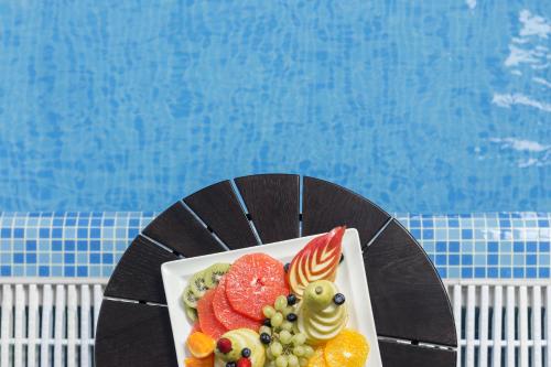 a plate of fruit on a table next to a pool at Novotel Jeddah Tahlia in Jeddah