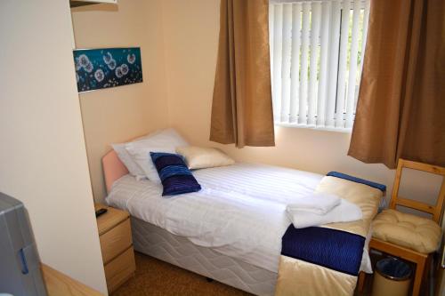 małe łóżko w pokoju z oknem w obiekcie Winston Guesthouse w mieście Bicester