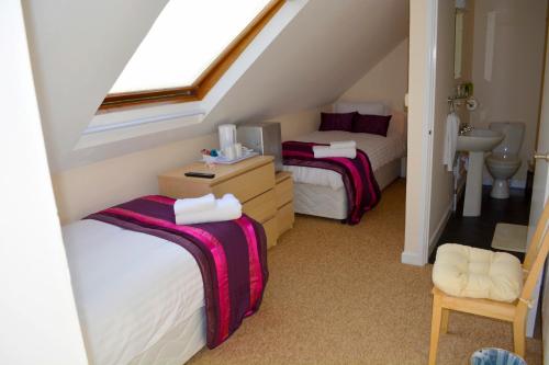 1 dormitorio en el ático con 2 camas y lavamanos en Winston Guesthouse en Bicester