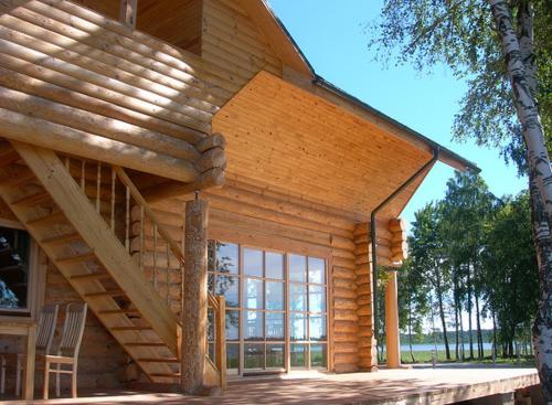 a wooden cabin with a wooden staircase on a deck at Holiday Complex Cirmas Ezerkrasts in Ludza