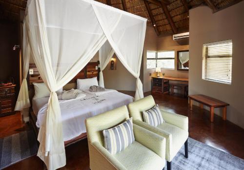a bedroom with a bed and two chairs in a room at Vuyani Safari Lodge in Hoedspruit