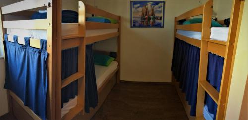 a room with three bunk beds with blue curtains at Hostel Marina Trogir in Trogir