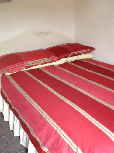 a red and white bed with red sheets at Rutland cottage in Largs