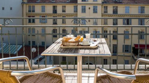 uma bandeja de comida numa mesa numa varanda em Hotel Solara em Nice